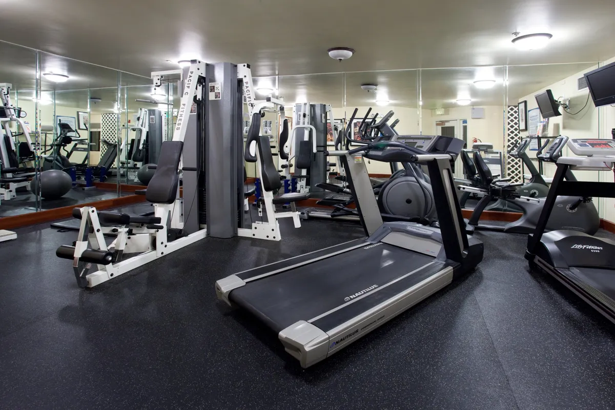 The fitness center is shown with treadmills, weight machines, and exercise balls. The area is bright and well-equipped, inviting guests to stay active during their visit.