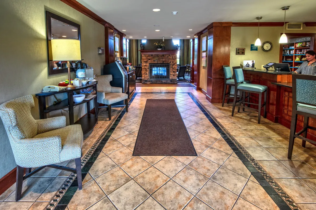 A warm, inviting interior space with a cozy fireplace, reception desk, and a comfortable seating area where guests are mingling and enjoying refreshments. The atmosphere is social and welcoming, ideal for evening receptions or casual gatherings.