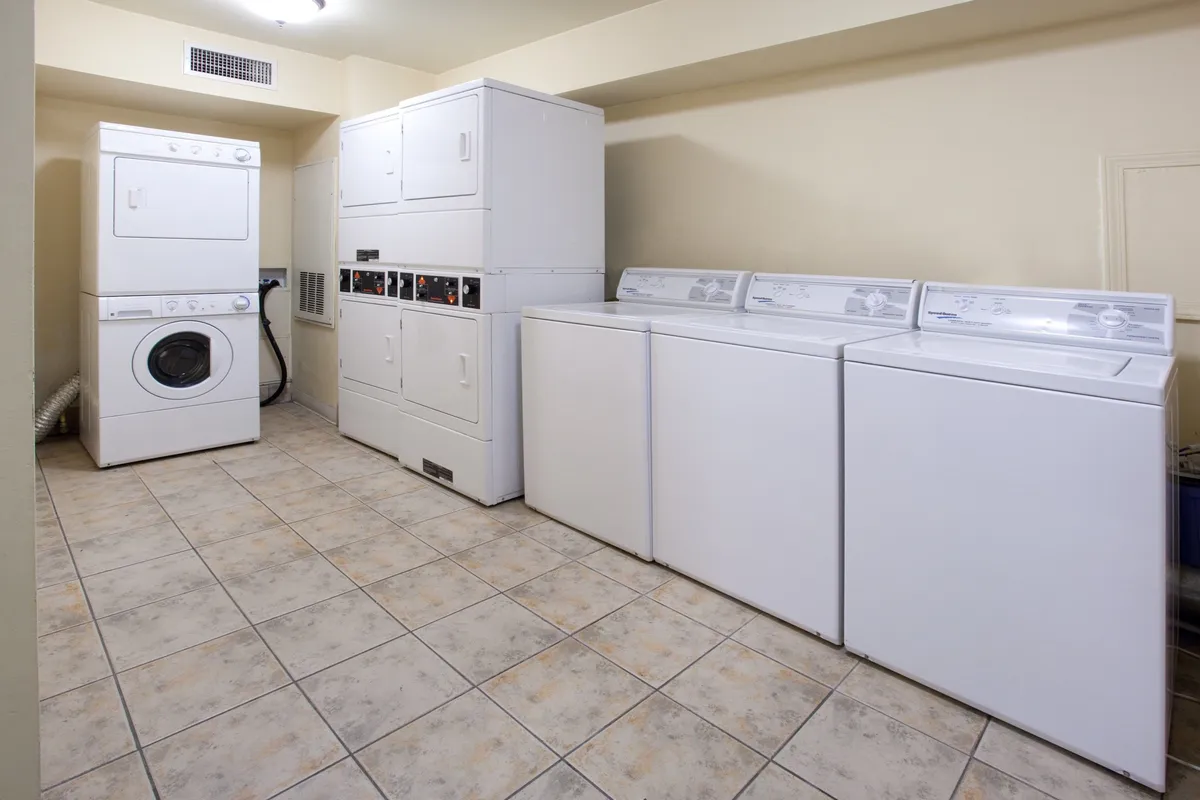 This image features a modern laundry area with both a washing machine and a drying machine. The space is clean and organized, showcasing the self-serve laundry amenities available to guests, with ample space for sorting and folding clothes.