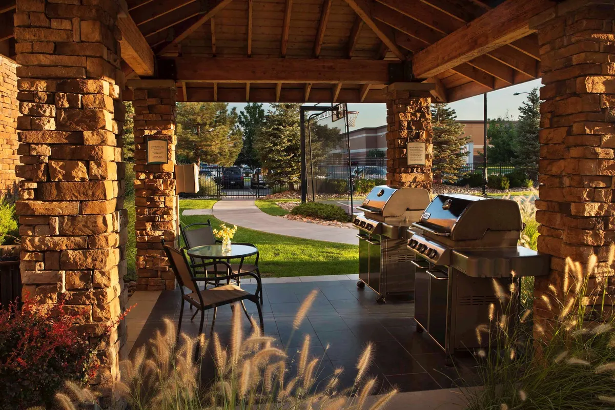 This image captures the property's outdoor grilling area and seating, surrounded by lush greenery. The setting is lively and welcoming, with space for families to gather, barbecue, and enjoy the outdoors together—ideal for shared experiences and relaxation after a day exploring Denver.